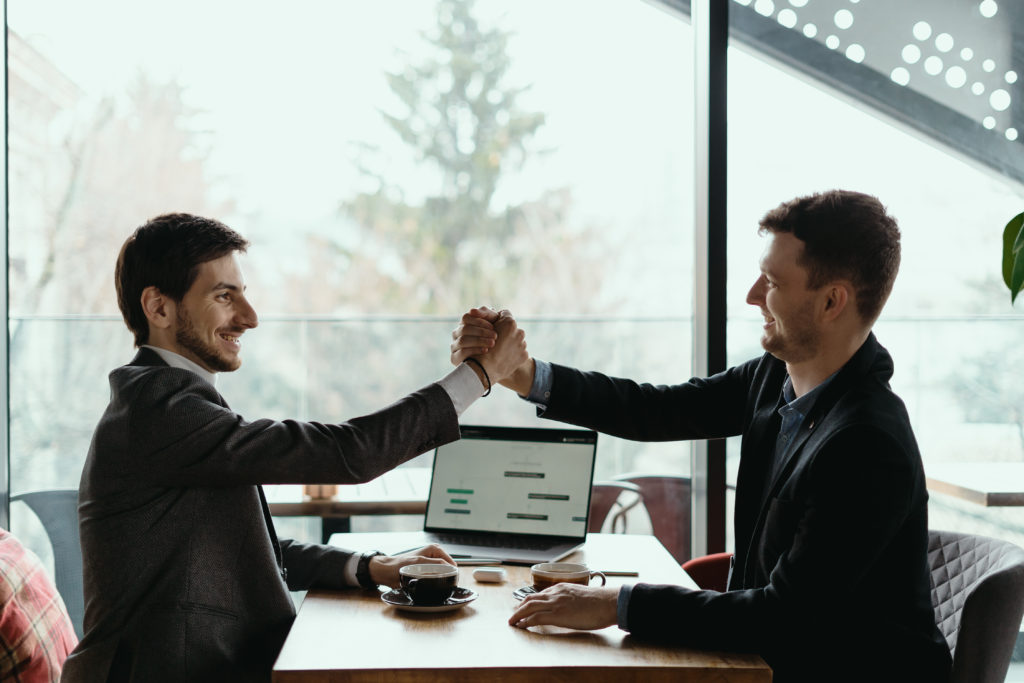 Como testar ideias: Dois homens de negócios comemorando um acordo ao encontrar uma solução para seu negócio, após ter encontrado um problema.